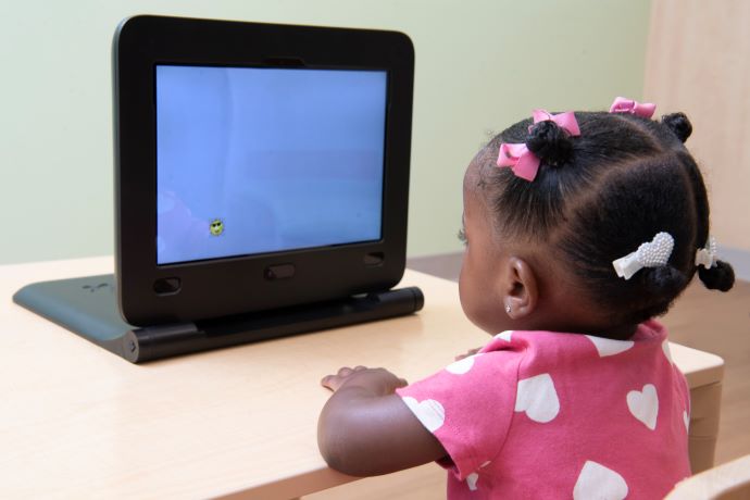 Child watching tablet video with drawing of a sun with sunglasses, depicting eye-tracking device that can aid with autism diagnoses