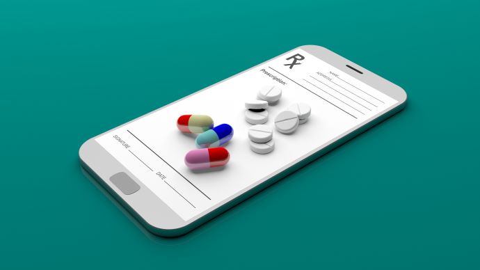 Cell phone with different colored pills on top with green background 