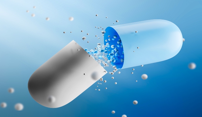 Large open white and blue pill with medicine leaking from it over a blue background.