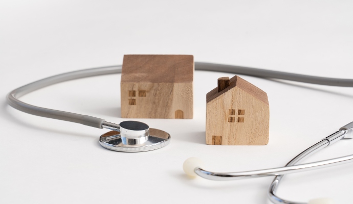 Two wooden house models and stethoscope around them. 