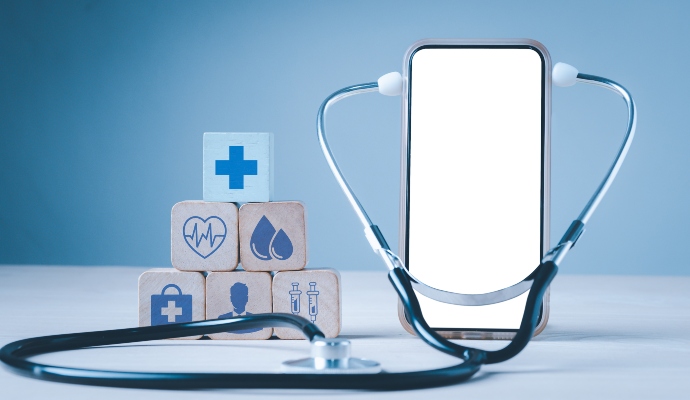Smartphone with stethoscope around it next to blocks with medical images against a blue background
