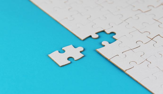 Two puzzle pieces coming together, denoting merger and acquisition activity 