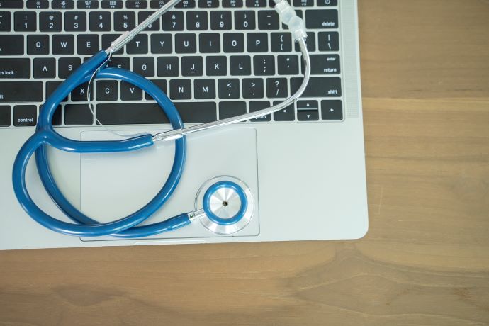 Blue stethoscope on laptop sitting on top of a desk